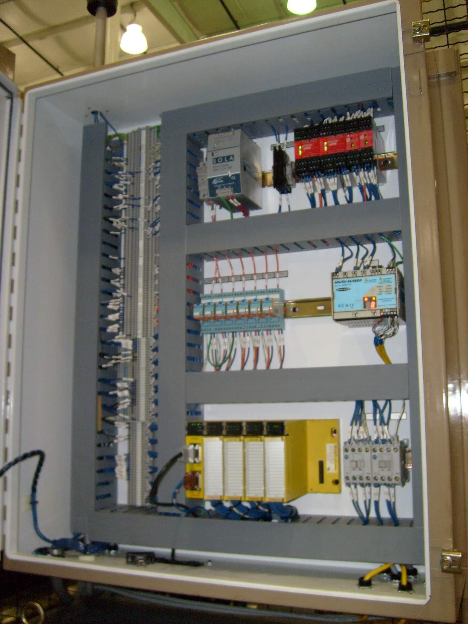 Open control panel with PLC, safety module, and terminal blocks