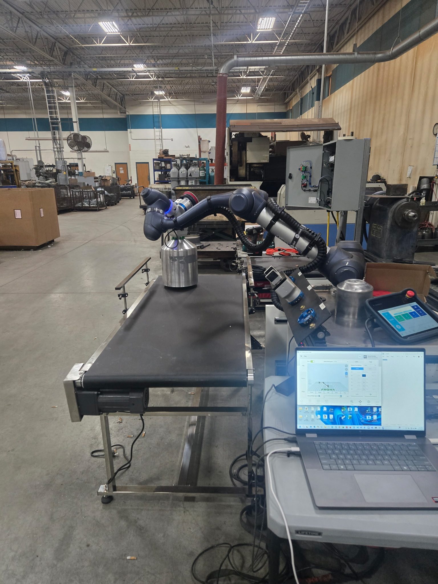 Robot arm being programmed from a laptop on the shop floor